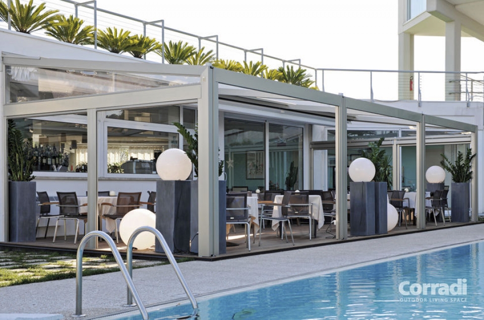 Pergotenda di design autoportante e di colore bianco collocata a bordo piscina